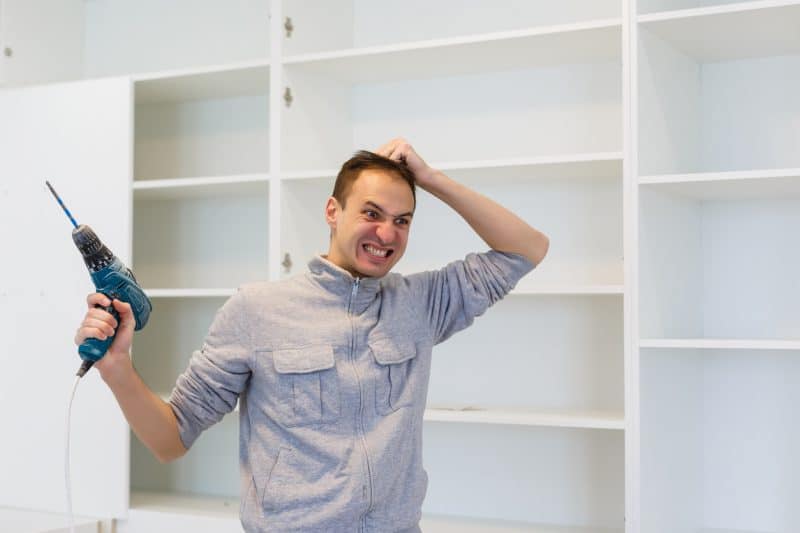 Homem estressado porque não sabe como desmontar guarda-roupa 