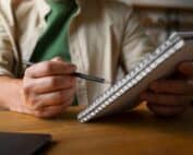 homem com caderno espiral e lápis nas mãos