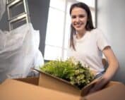 Mulher transportando plantas em mudança